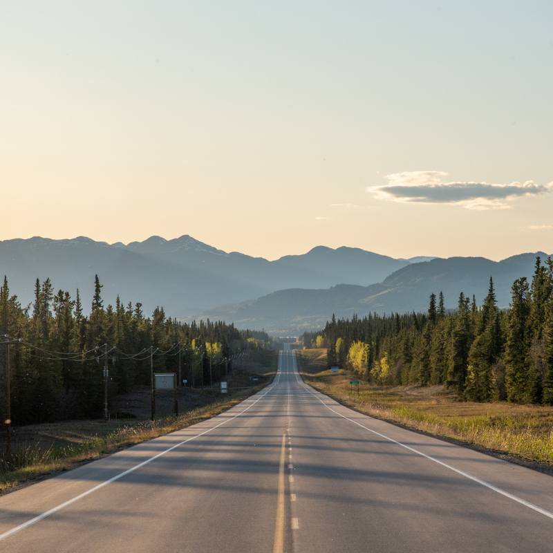 Weg die richting de imposante bergen leidt in Yukon Territory, Noord-Canada